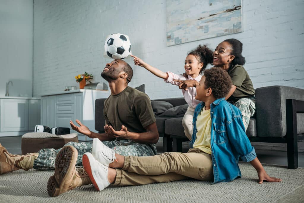 Woman and man in army uniform with their children playing with football ball